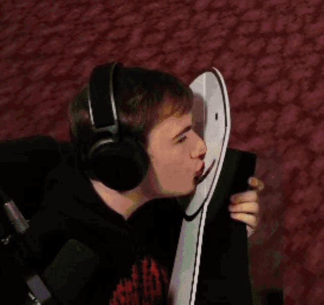 a man wearing headphones is kissing a remote control