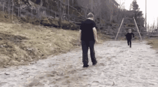 a man in a black shirt walks down a dirt road