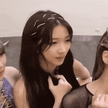 a woman is holding another woman 's hair while they are sitting next to each other .