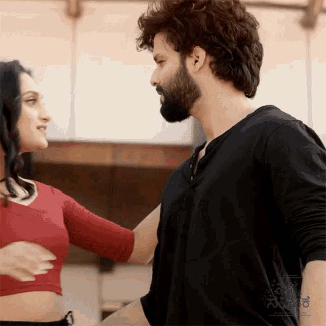 a man with a beard and a woman in a red crop top are dancing