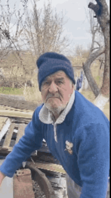 an elderly man wearing a blue sweater and a beanie