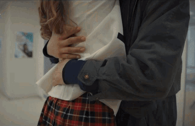 a woman in a plaid skirt is being held by a man in a black jacket