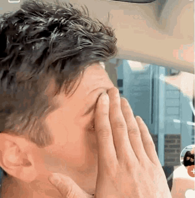 a man is covering his face with his hands while sitting in a car