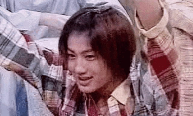 a close up of a person wearing a plaid shirt and tie .