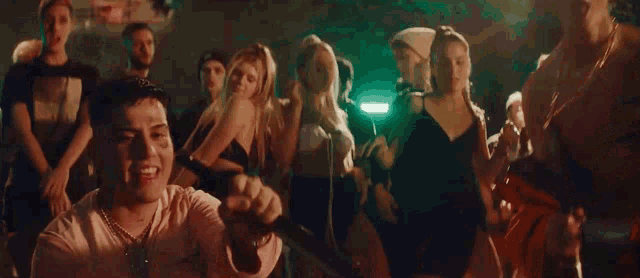 a man in a white shirt is surrounded by a crowd of people dancing