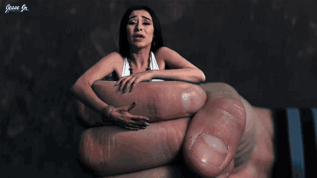 a woman is sitting on a person 's hand with the name jessie jr. on the bottom right