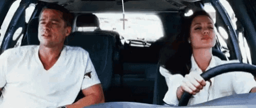 a man and a woman are driving in a car .