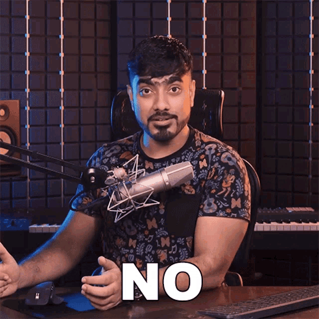 a man sitting in front of a microphone with the word no on his face