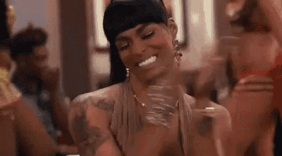 a woman is smiling and clapping her hands in a room with other women .