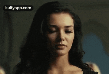 a woman with long dark hair is looking at the camera .