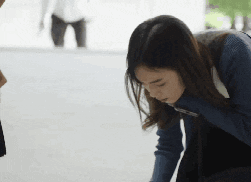 a woman in a blue sweater is kneeling down on the ground