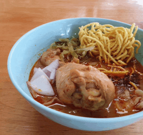 a bowl of soup with noodles chicken and onions