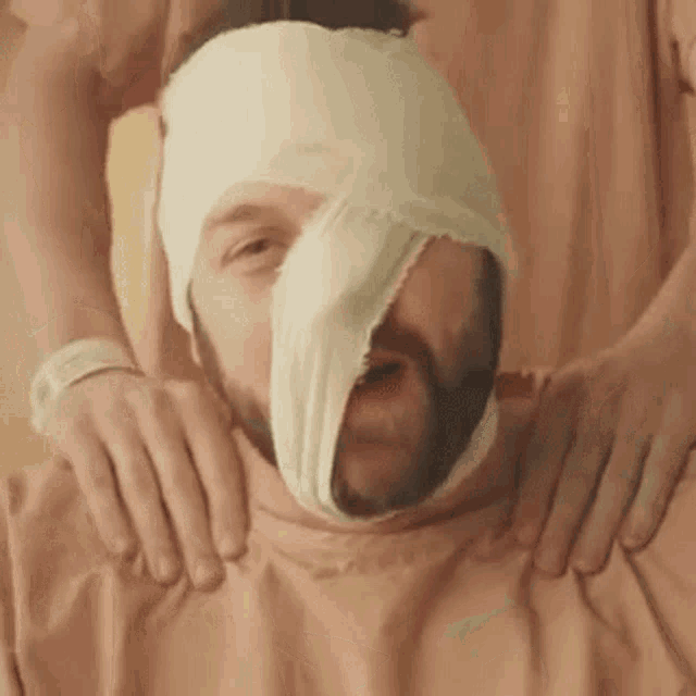 a man with a bandage on his head is being massaged by a woman .