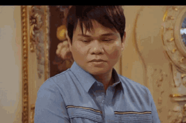 a man in a blue shirt is sitting in front of a clock and a painting .