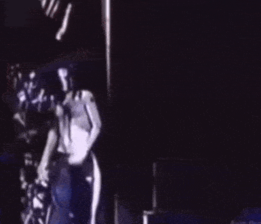 a man without a shirt is standing on a stage with a microphone .