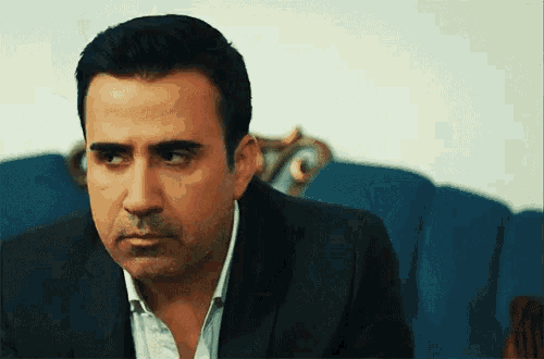 a man in a suit is sitting on a blue chair