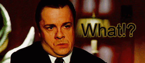 a man in a suit and tie is asking the question " what ? "