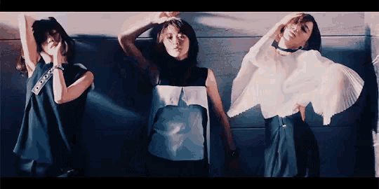 three women are standing next to each other with their arms outstretched and one has a blue shirt on