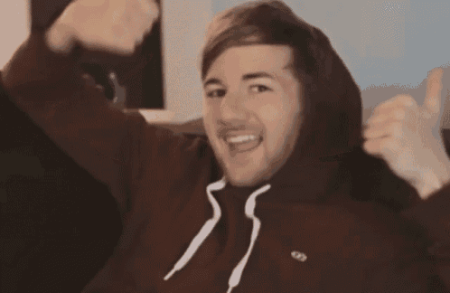 a man in a maroon hoodie gives a thumbs up