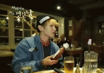 a man sitting at a table holding a bottle of beer and a glass of beer