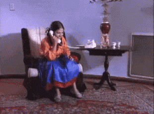 a woman is sitting in a chair talking on a telephone