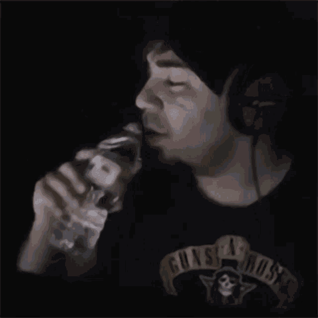 a man wearing a guns n roses shirt drinks water