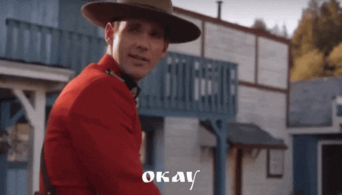 a man in a red uniform is standing in front of a building with the word okay written on it