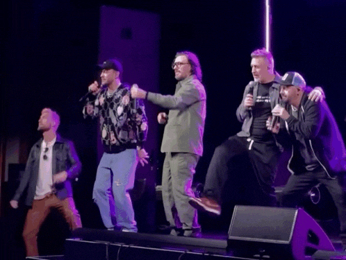 a group of men are standing on a stage with microphones in their hands