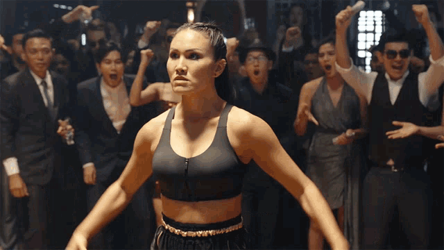 a woman stands in front of a crowd wearing a sports bra that says boxing on it