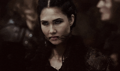 a woman with a snake in her mouth looks at the camera .