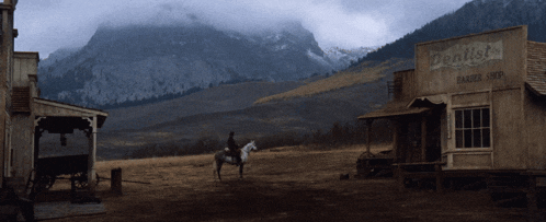 a man rides a horse in front of a dentist barber shop