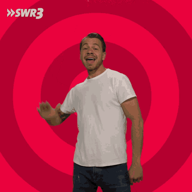 a man in a white shirt is waving his hand in front of a red circle with swr3 written on it