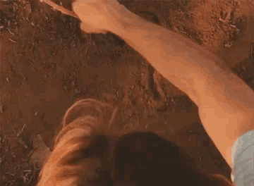 a person is laying on the ground with a stick in their hand and a foreign language written on the ground .