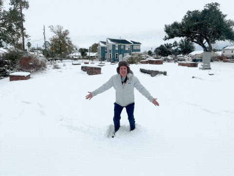 a man wearing an under armour jacket stands in the snow with his arms outstretched