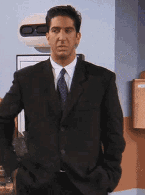 a man in a suit and tie standing with his hands in his pockets