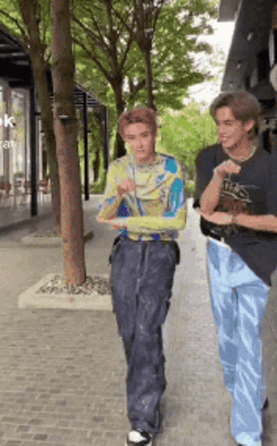 two young men are walking down a sidewalk and one of them is wearing a t-shirt that says ' tigers '