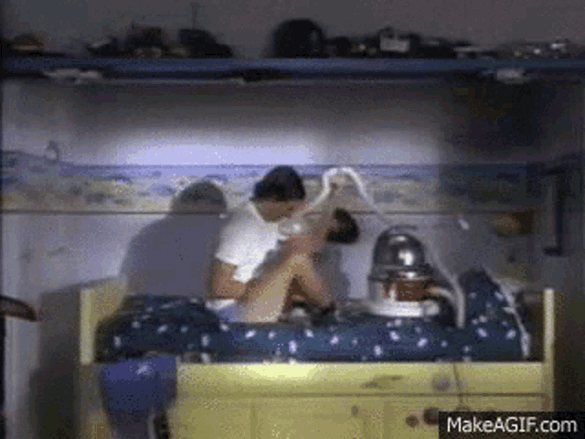 a couple laying on a bed with a vacuum cleaner on it