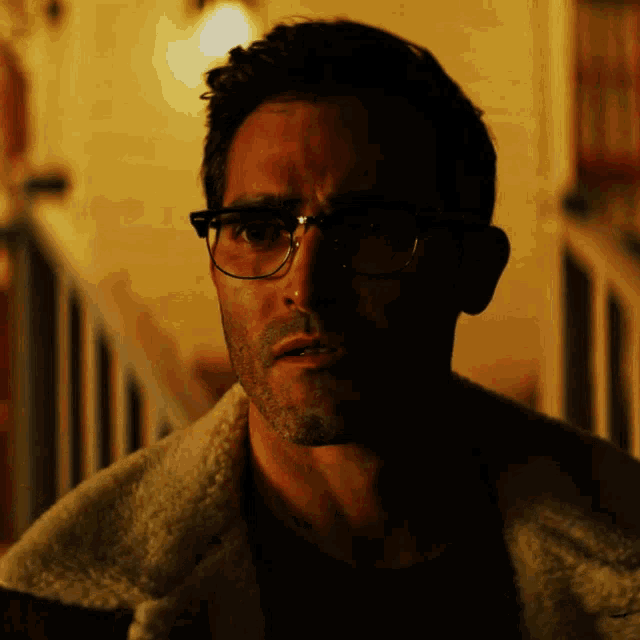 a close up of a man wearing glasses and a white jacket
