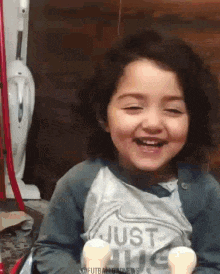 a little girl is smiling and holding two ice cream cones in her hand .