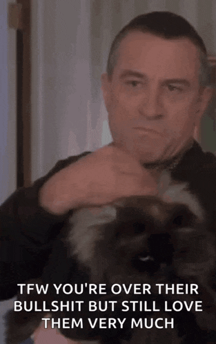 a man is holding a cat in his arms and the cat is looking at the camera .