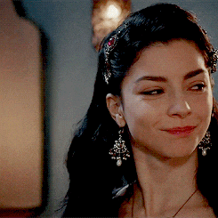 a woman wearing a headband and earrings smiles