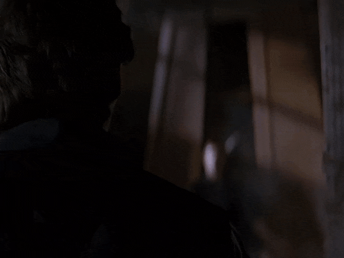 a man in a striped shirt is standing in a dark room with his arms outstretched