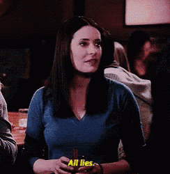 a woman in a blue sweater is holding a glass of beer and saying all lies .