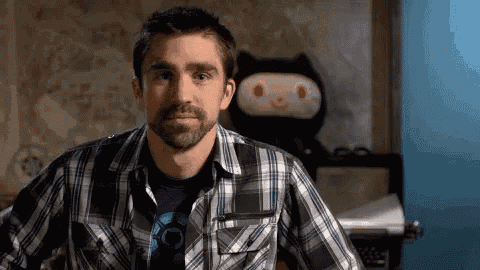 a man in a plaid shirt is standing in front of a stuffed cat .