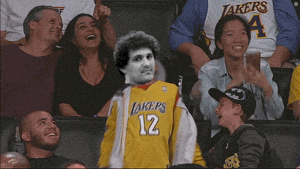 a man wearing a yellow lakers jersey stands in the crowd