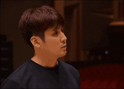 a man with red hair is wearing a black shirt and looking to the side