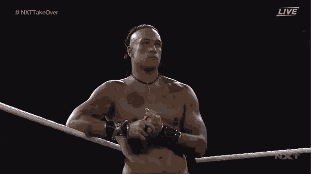 a shirtless wrestler is standing in a wrestling ring with the hashtag # nxt takeover