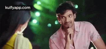 a man is singing into a microphone while talking to a woman .