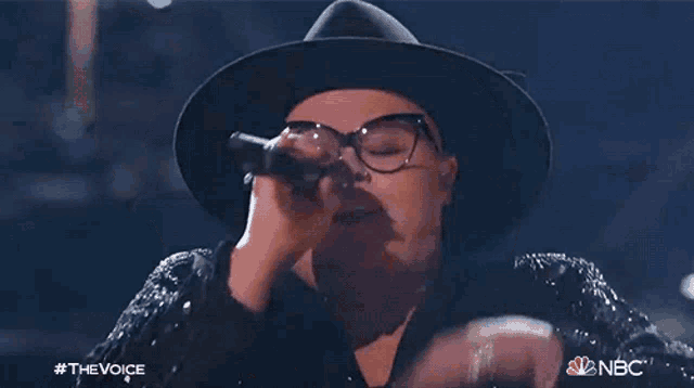 a woman singing into a microphone with the nbc logo on the bottom
