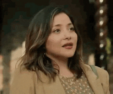 a close up of a woman wearing a tan coat and a floral dress .